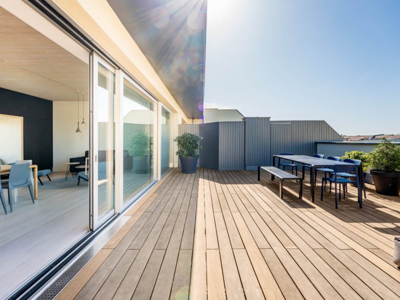 Hardwood rooftop patio deck with a picknick table and chairs. Floor to ceiling sliding doors open up to the loft apartment.